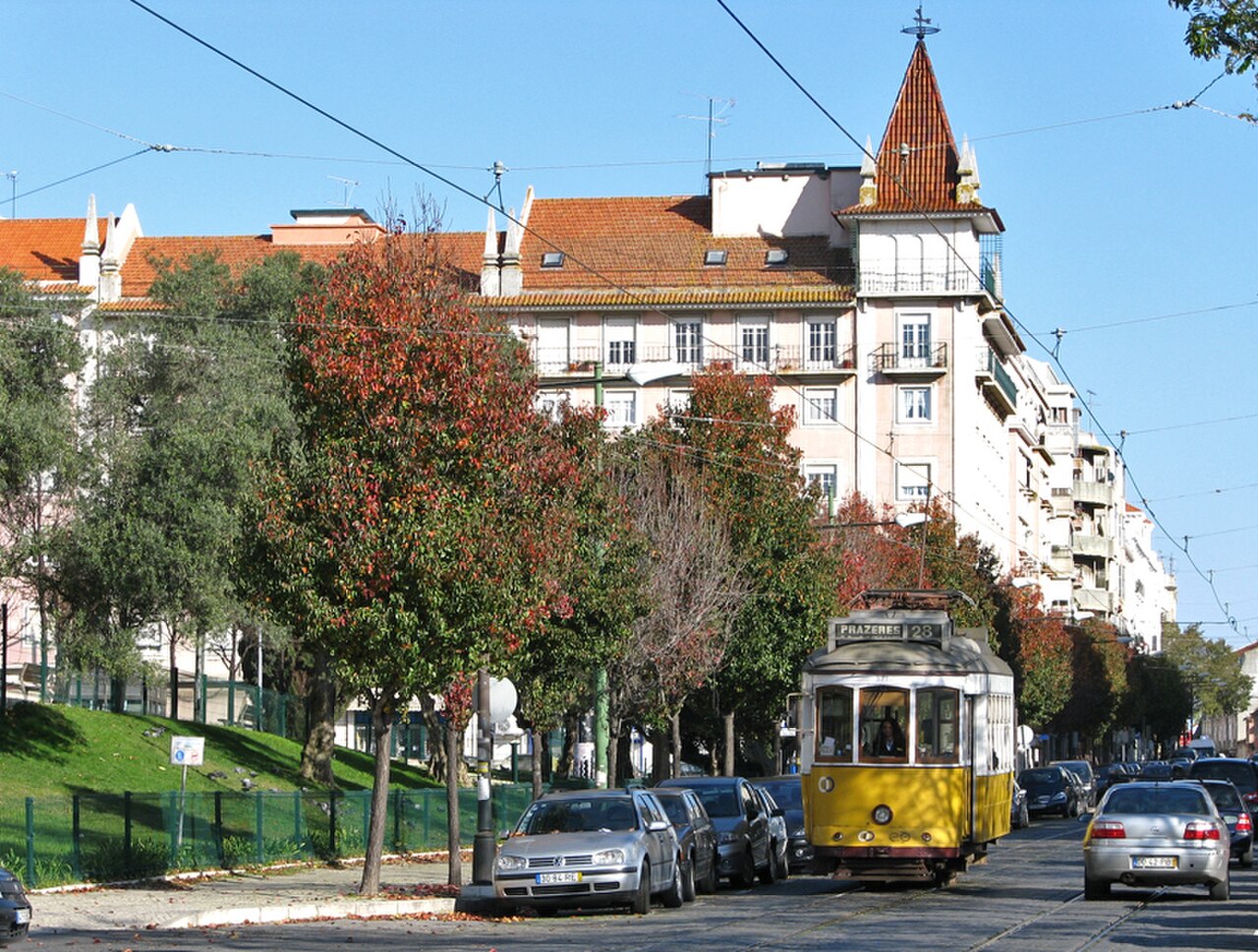 Campo de Ourique neighbourhood, with a yellow vintage tram passing tree-lined streets.